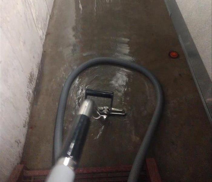 an extractor wand sucking out water from a concrete hallway