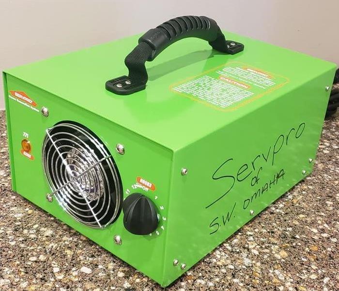 A green, SERVPRO, piece of equipment called the Ozone Generator on a graygranite table top