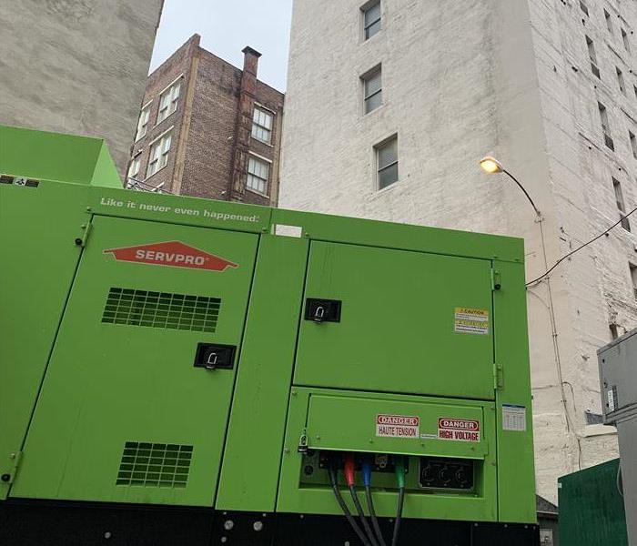 A green machine in the bottom of the picture with a tall grey building in the background.