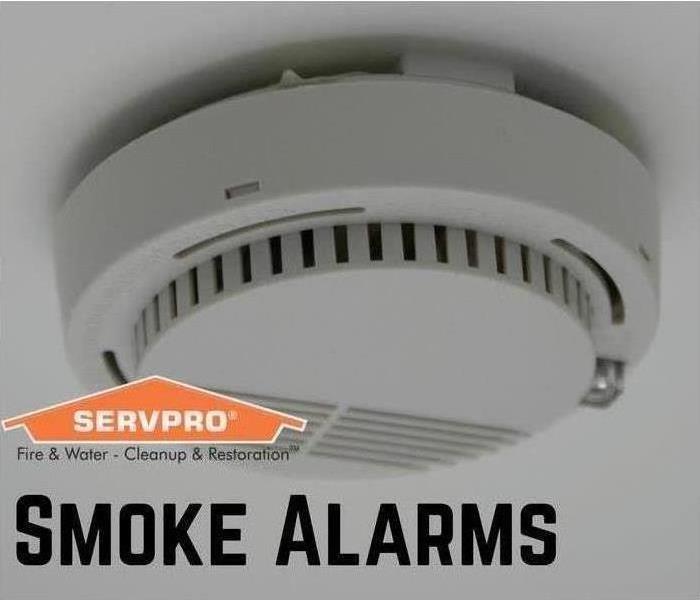 A smoke alarm on a ceiling, SERVPRO logo, states Smoke Alarms