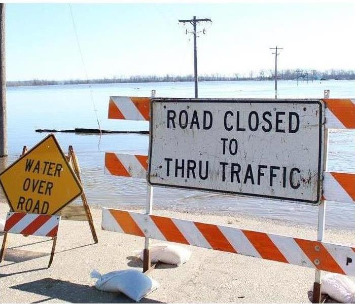 flood waters in distance, road block with Flood Waters Signs and road closed to through traffic sign posted